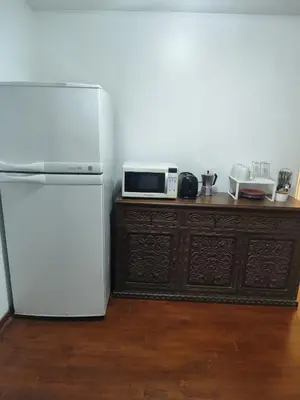 a kitchen with a white refrigerator and a microwave at Cómoda y céntrica habitación Larcomar in Lima