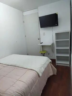 a bedroom with a bed and a flat screen tv at Acogedora y céntrica habitación Larcomar in Lima