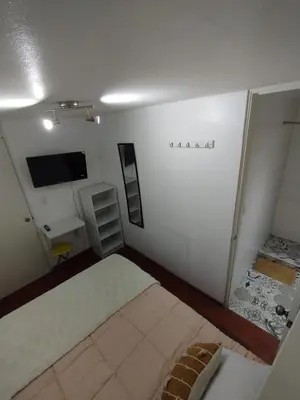 a small room with a bed and a television at Acogedora y céntrica habitación Larcomar in Lima