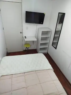 a bedroom with a bed and a desk and a tv at Acogedora y céntrica habitación Larcomar in Lima