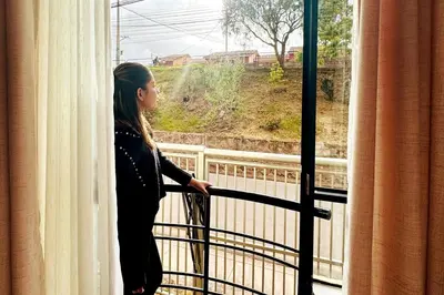 a woman looking out the window of a hotel room at Departamento en Cusco NAIRA in Cusco