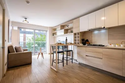 a kitchen with white cabinets and a bar with a stool at Art&U Apartments by Vibrant in Lima