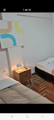 a room with two beds and a table with a lamp at Hostal Qori in Urubamba