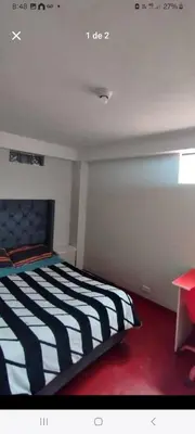a bedroom with a black and white bed and a table at Hostal Qori in Urubamba