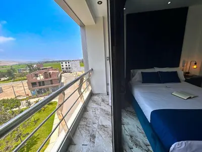 a bedroom with a bed and a balcony with a view at Hotel BlueThree Chancay in Chancay