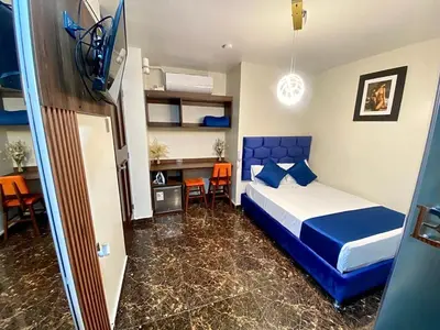 a bedroom with a blue bed and a desk and chairs at Hotel BlueThree Chancay in Chancay