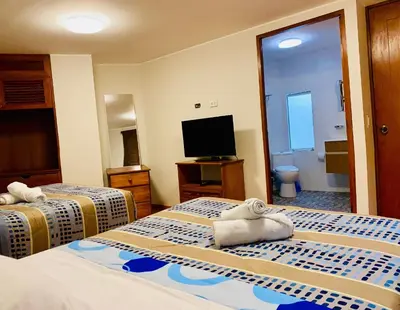 a hotel room with two beds and a flat screen tv at Suite Independiente con Baño Privado – Miraflore in Lima