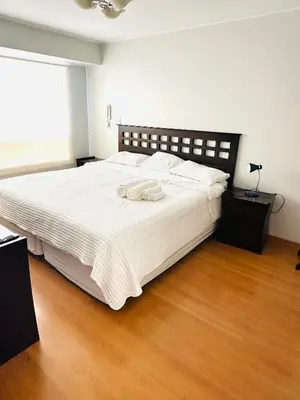 a bedroom with a large white bed with a wooden floor at Apartamento San Borja in Lima