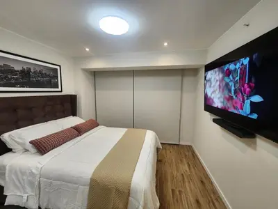 a bedroom with a bed and a flat screen tv at Elegante Departamento de Estreno en Centro Financiero in Lima