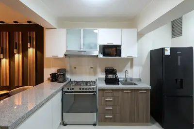 a kitchen with a stove and a refrigerator at Apartamento moderno cerca del Parque Wallenberg in Lima