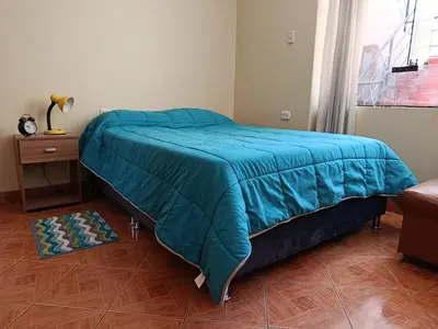 a bed with a blue comforter in a bedroom at bambanhouse in Cusco
