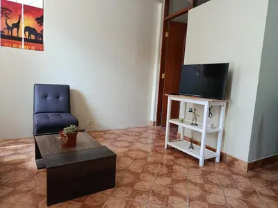 a living room with a blue chair and a tv at bambanhouse in Cusco