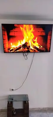 a tv hanging on a wall with a fire at Casa rústica in Ica