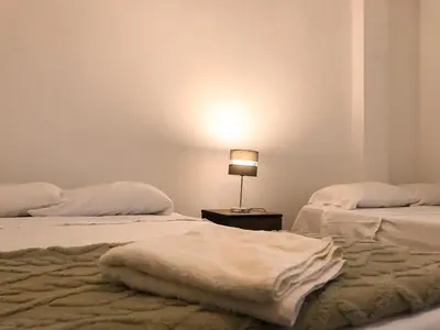 two beds in a room with a lamp on a table at Mini departamento con cochera in Ayacucho