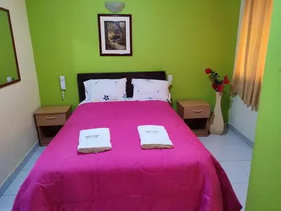 a bedroom with a pink bed with two towels on it at Hotel Misky Samay in Ayacucho