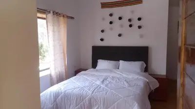 a bedroom with a white bed and a window at Casa tarawasy hostel in Urubamba