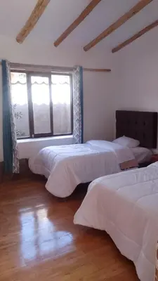 a bedroom with three beds and a window at Casa tarawasy hostel in Urubamba