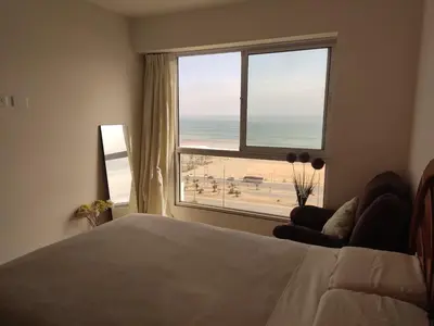 a bedroom with a bed and a view of the beach at Departamento Costa Verde San Miguel in Lima