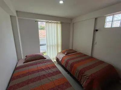two beds in a room with a window at Apartamento en Cusco III in Cusco