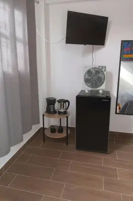 a room with a black refrigerator and a television at Suspiros de arica in Arica