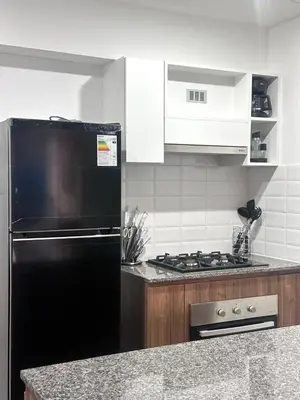 a kitchen with a black refrigerator and white cabinets at moderno departamento con vista al mar en miraflores in Lima