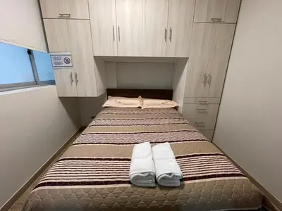 a bed in a small room with two towels on it at Casa de Moño - Moderno apartamento cerca a Aeropuerto y Terminal Terrestre in Lima