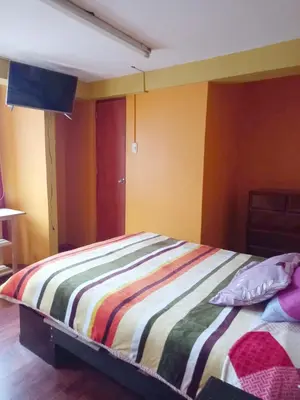 a bedroom with a bed with a striped blanket at Hospedaje Bienvenidos a mi Casa in Cerro de Pasco