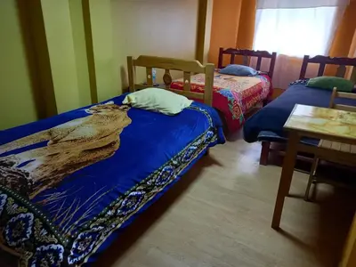 a bedroom with two beds and a table and a window at Hospedaje Bienvenidos a mi Casa in Cerro de Pasco