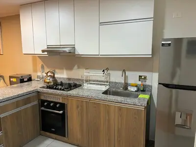 a kitchen with white cabinets and a sink and a stove at Spacious downtown apartment overlooking Parque de las Aguas in Lima