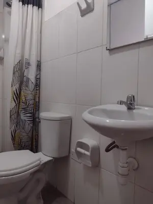 a white bathroom with a toilet and a sink at LA ACOGEDORA Qori Wasi in Ayacucho