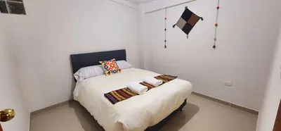 a small bedroom with a bed with white sheets and pillows at Vistas increíbles desde San Blas 4 in Cusco