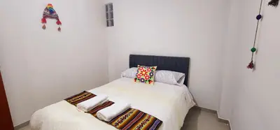 a small bedroom with a bed with white sheets and pillows at Vistas increíbles desde San Blas 4 in Cusco