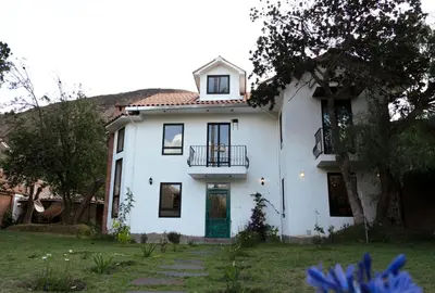 a white house with a porch and a balcony at Casa Julia in Huayllabamba