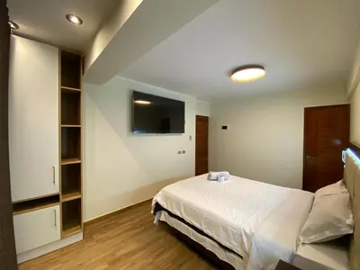 a bedroom with a white bed and a tv at Hotel Sonccollay in Huancayo