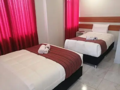 two beds in a hotel room with red curtains at Belys inn in Cusco