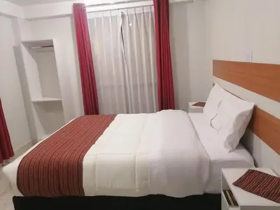 a bedroom with a white bed with a red curtain at Belys inn in Cusco