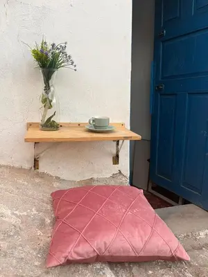a red pillow sitting on the ground next to a table at super cute affordable mini apt, san Blas in Cusco