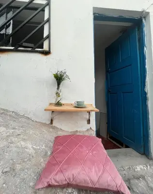 a pink pillow on the ground next to a table with a blue door at super cute affordable mini apt, san Blas in Cusco