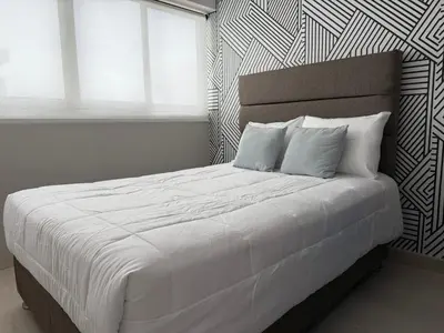 a bed with white sheets and pillows in a bedroom at Departamento Vizuale in Lima