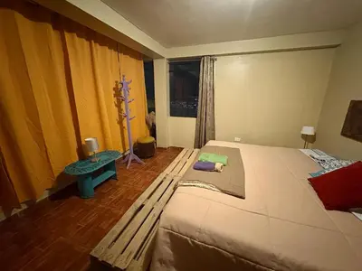 a bedroom with a large bed and a table at New colorful & artsy home, fam perfect, great wifi for working in Cusco