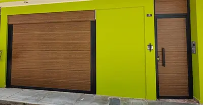 two wooden garage doors on a green wall at La casa de Betty in Huancayo