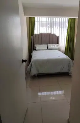 a bedroom with a bed and a window with green curtains at La casa de Betty in Huancayo
