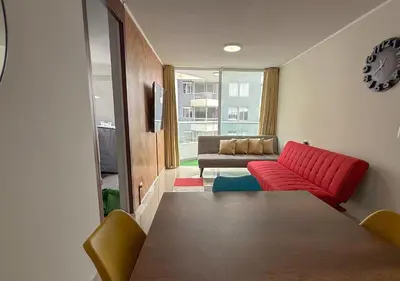 a living room with a red couch and a table at Dpto exclusivo en San Miguel con piscina y gym in Lima