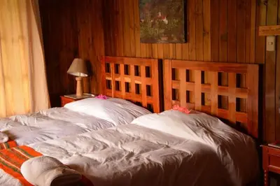 two twin beds in a bedroom with wood walls at Altares de Oxapampa in Oxapampa