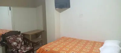a bedroom with a bed and a chair and a tv at Hospedaje El Encanto in Huancayo