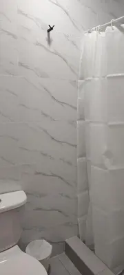 a white bathroom with a toilet and a shower at Los Pulpos in Bombiso