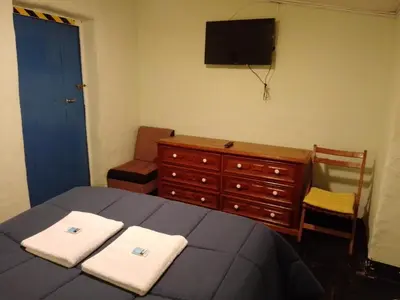 a bedroom with a bed and a dresser and a television at Casa Margarita in Cusco
