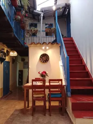 a table with two chairs and a clock and stairs at Casa Margarita in Cusco