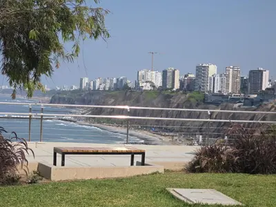a bench sitting next to a beach with a city at Barranco blue sea in Lima