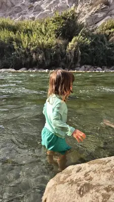 a little girl standing in the water in a river at San Jerónimo River Lodge in Lunahuaná